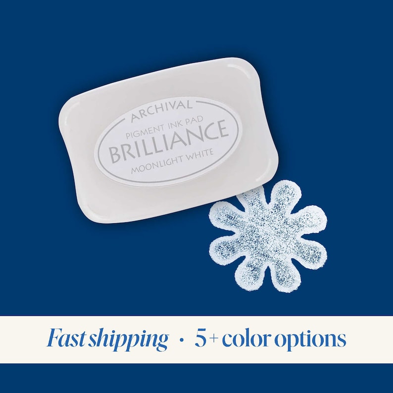 K&ouml;nnte beinhalten: Archival Pigment Tintenkissen in Moonlight White von Brilliance. Das Tintenkissen ist wei&szlig; und hat einen blauen Hintergrund. Das Tintenkissen hat die Form eines Rechtecks mit abgerundeten Ecken. Das Tintenkissen liegt auf einer blauen Oberfl&auml;che.