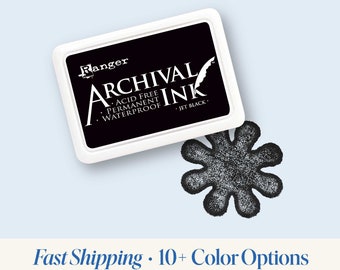 May include: A black ink pad with the text "Ranger Archival Ink Acid Free Permanent Waterproof Jet Black" on the top. The ink pad is open and a black ink stamp of a six-pointed star is visible.