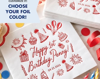 May include: A white square paper napkin featuring red foil-stamped birthday graphics including balloons, party hats, cupcakes, gifts, and fireworks. The text reads Happy 1st Birthday, Penny! and the date 09.25.2026 in a script font.