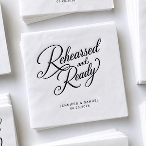 May include: A square white paper napkin featuring black embossed calligraphy that reads Rehearsed and Ready. Below the text, the names Jennifer & Samuel and the date 06.20.2026 are printed in a simple black sans-serif font. The napkin is stacked.
