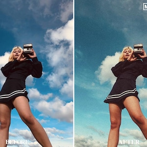 May include: A woman wearing a black skirt with white stripes and a black top, holding a vintage camera, poses against a blue sky with white clouds.
