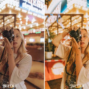 May include: A person taking a photo with a vintage camera in front of a brightly lit building with a sign that says "Eat Fresh".