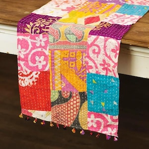 May include: A rectangular table runner featuring a patchwork design of various cotton fabric squares in vibrant colors including pink, yellow, purple, and teal. The fabric displays diverse floral and geometric patterns with visible white kantha stitching.