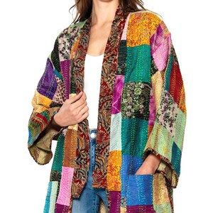 May include: A long-sleeved open-front jacket featuring a vibrant patchwork design with various floral and geometric patterns in shades of yellow, purple, green, blue, and red. The garment includes two front pockets and visible white stitching.