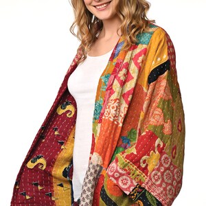 A vibrant patchwork kimono-style jacket featuring a fun mix of colors and patterns, including bright tones with floral, geometric, and abstract designs. The jacket has wide sleeves, a relaxed fit, and visible hand-stitching, creating a boho look.