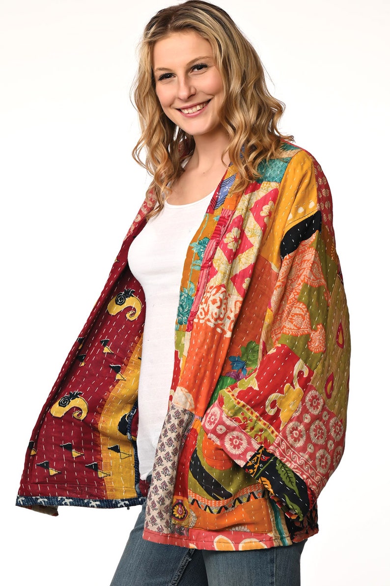 A vibrant patchwork kimono-style jacket featuring a fun mix of colors and patterns, including bright tones with floral, geometric, and abstract designs. The jacket has wide sleeves, a relaxed fit, and visible hand-stitching, creating a boho look.