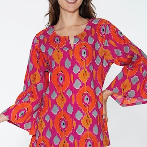 May include: A pink, orange, and gray patterned blouse with bell sleeves. The blouse has a V-neck and a relaxed fit.