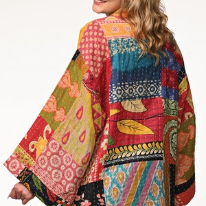 A vibrant patchwork kimono-style jacket featuring a fun mix of colors and patterns, including bright tones with floral, geometric, and abstract designs. The jacket has wide sleeves, a relaxed fit, and visible hand-stitching, creating a boho look.