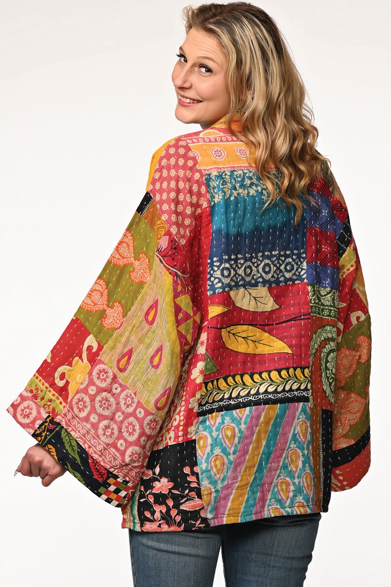 A vibrant patchwork kimono-style jacket featuring a fun mix of colors and patterns, including bright tones with floral, geometric, and abstract designs. The jacket has wide sleeves, a relaxed fit, and visible hand-stitching, creating a boho look.