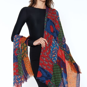 May include: A colorful patchwork scarf with a fringed edge. The scarf features a variety of floral and geometric patterns in shades of red, blue, green, orange, and yellow.