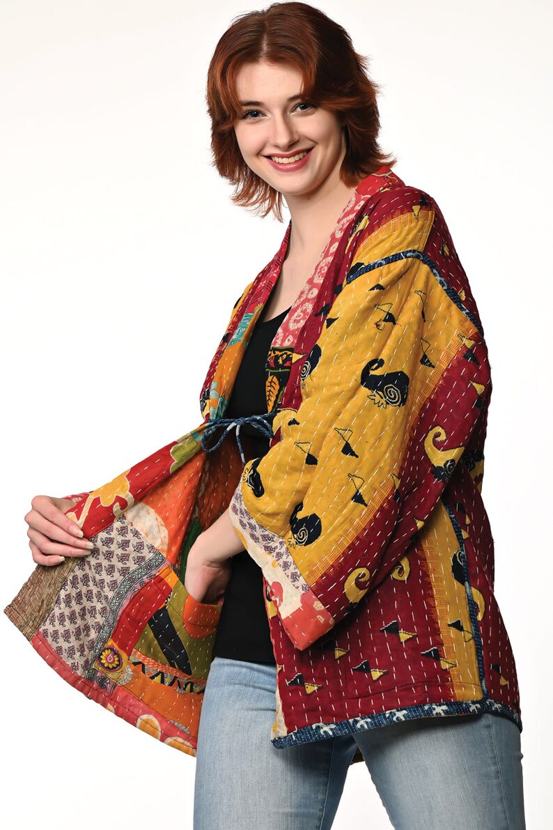 A vibrant patchwork kimono-style jacket featuring a fun mix of colors and patterns, including bright tones with floral, geometric, and abstract designs. The jacket has wide sleeves, a relaxed fit, and visible hand-stitching, creating a boho look.