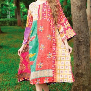 Könnte beinhalten: Ein buntes Patchwork-Kleid mit langen Ärmeln und rundem Ausschnitt. Das Kleid hat eine Mischung aus Mustern, darunter Blumen- und geometrische Designs. Das knielange Kleid wird mit schwarzen Stiefeln getragen. Das Kleid ist aus weichem Material.