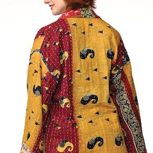 A vibrant patchwork kimono-style jacket featuring a fun mix of colors and patterns, including bright tones with floral, geometric, and abstract designs. The jacket has wide sleeves, a relaxed fit, and visible hand-stitching, creating a boho look.