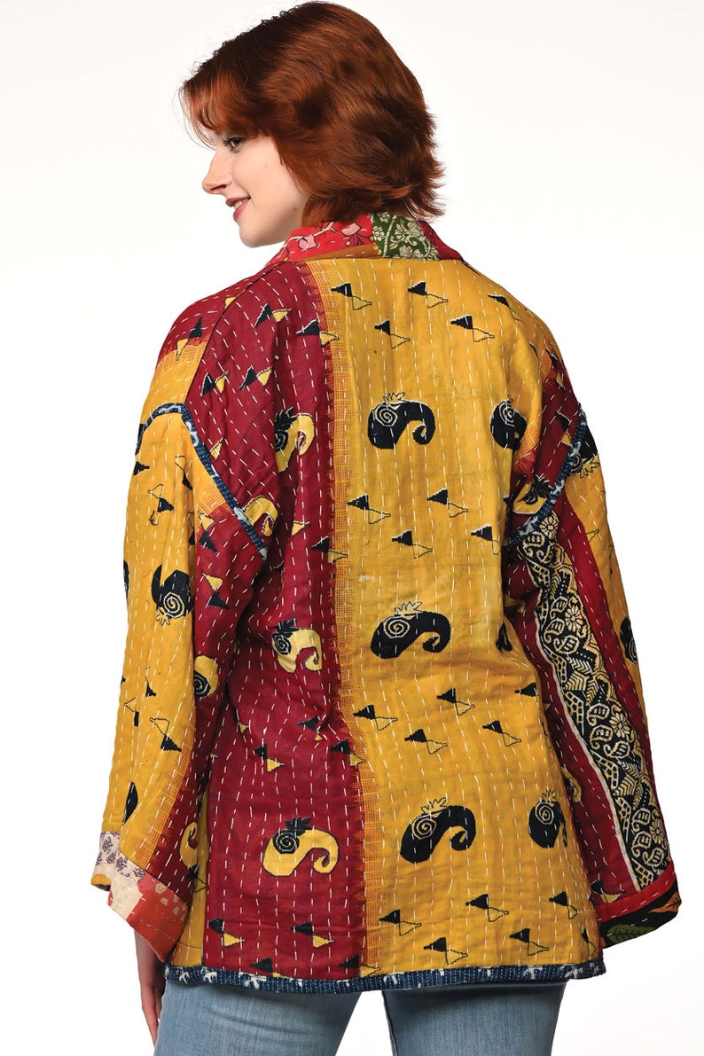 A vibrant patchwork kimono-style jacket featuring a fun mix of colors and patterns, including bright tones with floral, geometric, and abstract designs. The jacket has wide sleeves, a relaxed fit, and visible hand-stitching, creating a boho look.