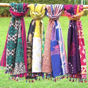 May include: Four rectangular scarves featuring intricate kantha stitching and vibrant, multi-colored patchwork patterns. Each scarf displays a unique combination of floral, geometric, and paisley prints in shades of green, yellow, blue, and purple, finished with small, colorful tassels along the bottom edges.