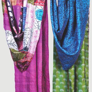May include: Two rectangular fabric throws featuring intricate kantha stitching. The left throw displays a patchwork of magenta, white, and multi-coloured floral patterns. The right throw features a deep blue floral print over a vibrant green base.