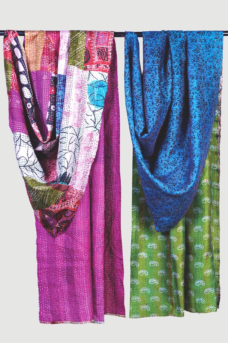 May include: Two rectangular fabric throws featuring intricate kantha stitching. The left throw displays a patchwork of magenta, white, and multi-coloured floral patterns. The right throw features a deep blue floral print over a vibrant green base.