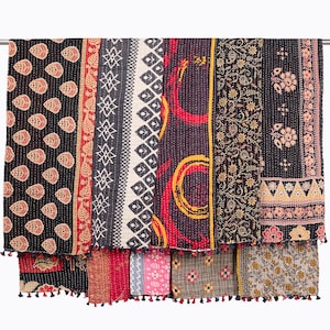 May include: A multi-panel textile quilt featuring a variety of printed patterns including repeating leaf shapes, geometric diamonds, circular motifs, and floral vines in black, red, yellow, and cream, finished with small decorative tassels along the edge.