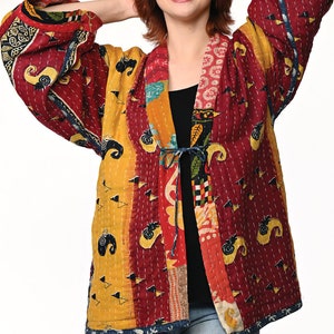 A vibrant patchwork kimono-style jacket featuring a fun mix of colors and patterns, including bright tones with floral, geometric, and abstract designs. The jacket has wide sleeves, a relaxed fit, and visible hand-stitching, creating a boho look.