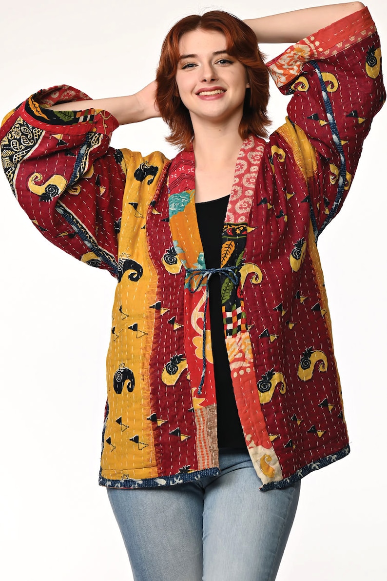 A vibrant patchwork kimono-style jacket featuring a fun mix of colors and patterns, including bright tones with floral, geometric, and abstract designs. The jacket has wide sleeves, a relaxed fit, and visible hand-stitching, creating a boho look.
