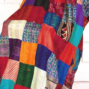 May include: A patchwork quilt featuring a variety of colourful fabric squares in shades of red, blue, orange, green, and purple. The textile displays intricate running stitch patterns throughout, creating a textured surface with diverse floral and geometric prints.
