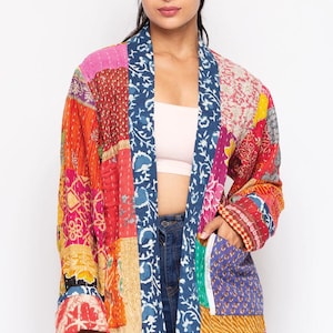 Puede incluir: Chaqueta tipo kimono de patchwork en colores vibrantes. La chaqueta presenta una mezcla de estampados florales y geométricos en rojo, naranja, rosa y azul. Tiene un corte holgado, mangas largas y bolsillos.