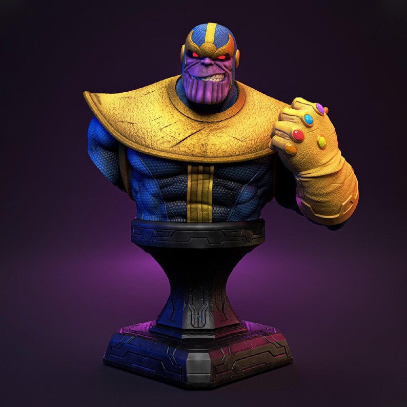 Op de afbeelding: Een Thanos borstbeeld. Het beeld toont een paarsgekleurd personage met een strenge uitdrukking, gekleed in een blauw en gouden outfit en een gouden handschoen versierd met kleurrijke edelstenen. Het borstbeeld is op een zwarte sokkel gemonteerd.