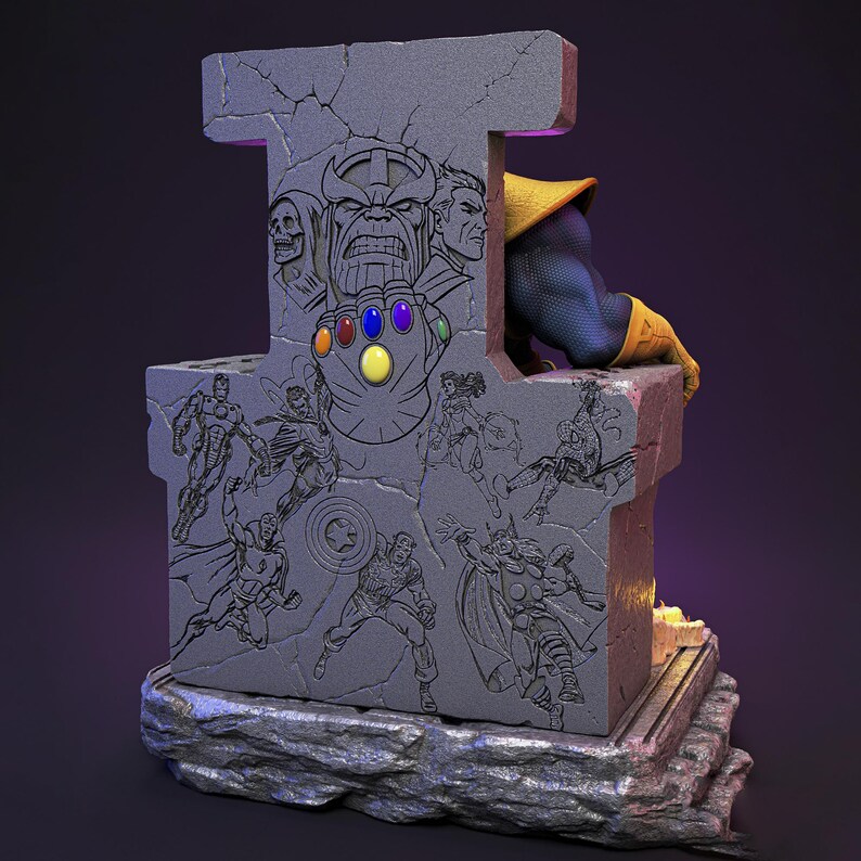Op de afbeelding: Een grijze stenen sculptuur met gegraveerde Marvel-personages, waaronder Thanos en de Infinity Gauntlet. De sculptuur heeft een paarse gloed en een figuur van Thanos in een geel en blauw pak zit erbovenop. De basis heeft een ruwe, steenachtige textuur.