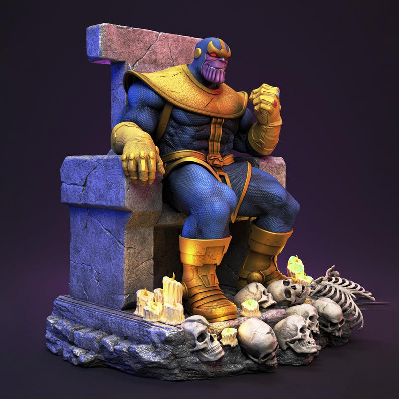 Op de afbeelding: Gedetailleerd beeldje van Thanos zittend op een stenen troon. Het figuur draagt een blauw en goud pak met een paars gezicht. De troon is omgeven door schedels, kaarsen en een skelet. Het kleurenschema is donker met paarse en gouden accenten.