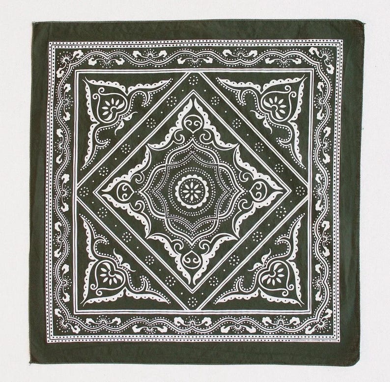 May include: Dark green bandana with a white ornate design. The square bandana features a central diamond pattern with floral and scroll details, surrounded by a decorative border. The design is symmetrical and detailed, creating a classic aesthetic.