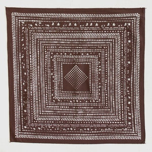 May include: A square, brown bandana with a white geometric pattern. The design features concentric squares and a central diamond shape, all composed of dots and lines. The bandana has a border with the text "ABRACADANA ALL COTTON MADE IN USA".