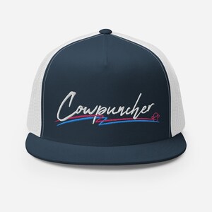 Pu&ograve; includere: Cappellino da camionista blu navy con retro in rete bianca. La parte anteriore presenta la scritta ricamata "Cowpuncher" in corsivo bianco, con linee rosse e blu sottostanti. Un piccolo simbolo a forma di cuore &egrave; a destra.