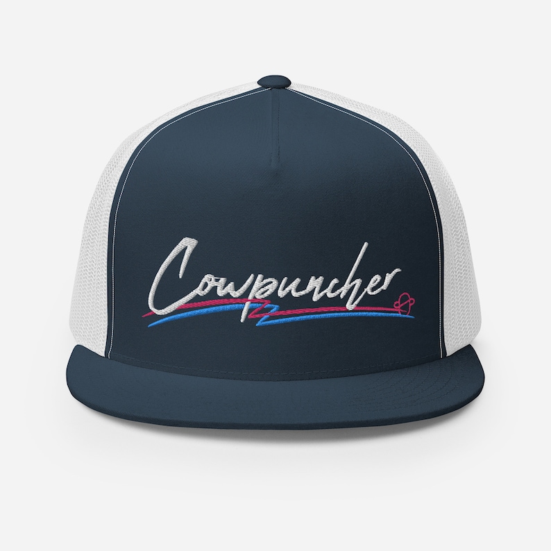 Pu&ograve; includere: Cappellino da camionista blu navy con retro in rete bianca. La parte anteriore presenta la scritta ricamata "Cowpuncher" in corsivo bianco, con linee rosse e blu sottostanti. Un piccolo simbolo a forma di cuore &egrave; a destra.