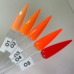 May include: Five nail polish color samples in shades of orange and red, displayed on clear plastic sticks. Each stick has a white label with a number from 01 to 05. The colors range from light orange to a vibrant red.