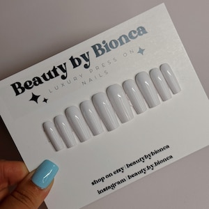 May include: A set of ten white press-on nails. The nails are arranged in a row on a white card with the text "Beauty by Bionca Luxury Press On Nails" and contact information for the shop on Etsy and Instagram.