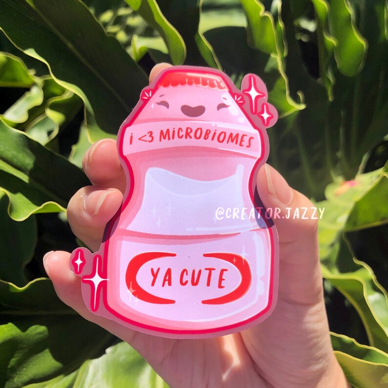 Może przedstawiać: R&oacute;żowa i czerwona kresk&oacute;wkowa ilustracja butelki jogurtu z uśmiechającą się twarzą i tekstem "i <3 microbiomes" i "ya cute" z przodu.
