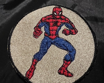 May include: A red and blue embroidered patch of Spiderman in a fighting pose on a white circle background.