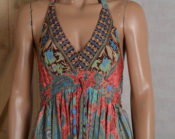 Könnte beinhalten: Halterneck-Kleid mit V-Ausschnitt. Das Kleid zeigt ein lebendiges Muster in Korallen-, Blau- und Brauntönen. Das Oberteil hat ein detailliertes Design, und der Rock besteht aus fließendem, gemustertem Stoff. Das Kleid ist aus leichtem Material.