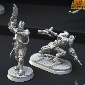 May include: Two gray 3D printed miniature figures of human cyborgs with mechanical limbs and weapons. The figures are posed in action stances. The text "Human Cyborgs" and "547" are printed below the figures.