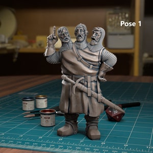 May include: A three-headed warrior figurine in a medieval style, with chainmail and a sword. The figure is posed on a blue cutting mat, with paint pots and brushes nearby. The text "Pose 1" is visible.
