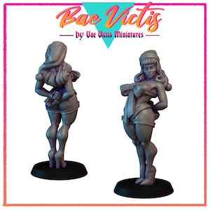 Può includere: Due figurine in miniatura grigie di donne in pose suggestive. Le figurine sono su basi nere. Il testo "Bae Victis" e "by Vae Victis miniatures" è nella parte superiore dell'immagine.