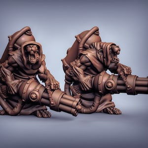 Pode incluir: Duas estatuetas marrons detalhadas de criaturas vestindo túnicas com capuz e segurando grandes armas multi-canhão intrincadas.