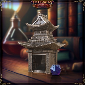 Puede incluir: Una miniatura de pagoda de color plateado con un interior negro y un dado de 20 caras azul oscuro y plateado delante. La torre es una pieza de juego en miniatura para el juego Tiny Towers: Fates End.