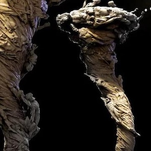 May include: A detailed sculpture of a twisted, tree-like form with figures climbing its surface. The sculpture has a textured, weathered appearance, with a dark background. The figures are small and appear to be struggling to climb.