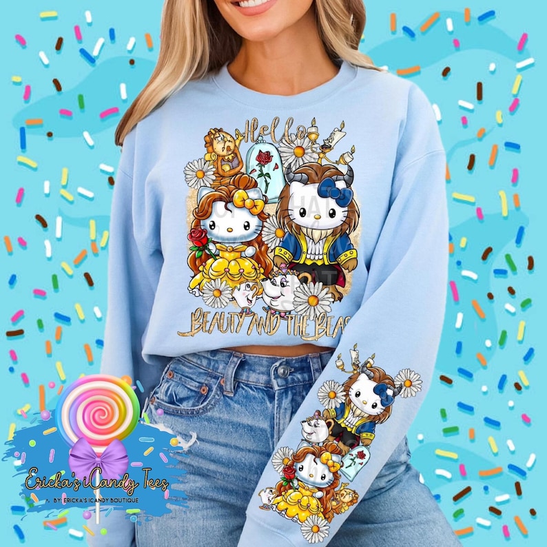 Puede incluir: Una sudadera azul claro con un estampado gr&aacute;fico de Hello Beauty and the Beast que presenta una imagen de dibujos animados de Bella y la Bestia como personajes de Hello Kitty. El gr&aacute;fico tambi&eacute;n incluye una rosa, una corona y un castillo.