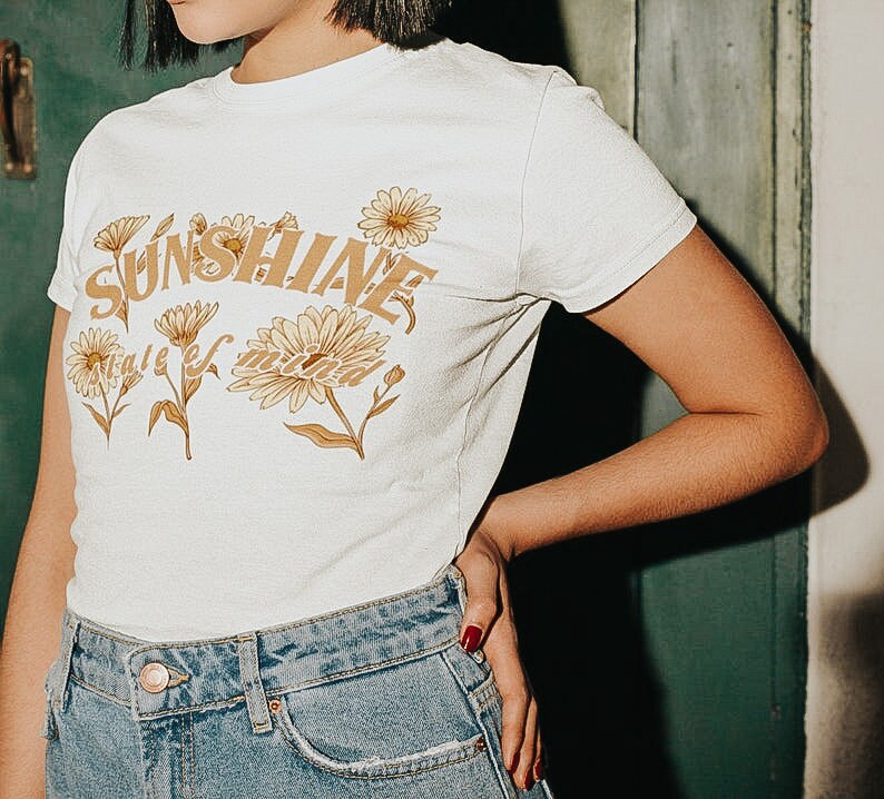May include: White t-shirt with a graphic print of yellow flowers and the text "Sunshine state of mind".