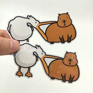 Pelican Bites Capybara Meme Sticker / Glossy & Holo Stickers