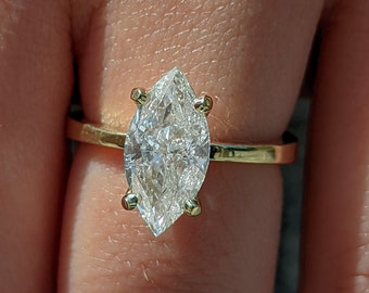 May include: A gold ring with a large, clear marquise-shaped diamond.