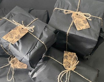 May include: Five black gift boxes wrapped in black tissue paper and tied with twine. Each box has a brown paper tag with a leaf design.