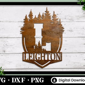 Puede incluir: Un letrero de madera marr&oacute;n con una silueta de un bosque y la palabra "LEIGHTON" en una fuente decorativa.